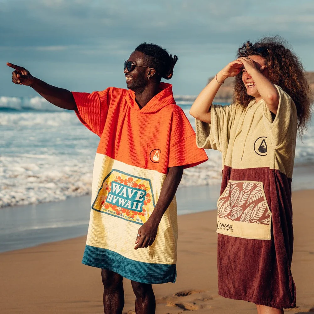 Ponchos von Wave Hawaii, zwei personen am Strand stehen mit Ponchos in bunten Farben